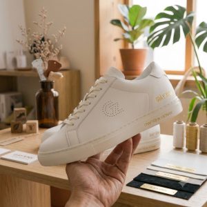 cận cảnh tay cầm giày sneaker nữ màu trắng đế bằng 3cm