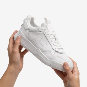 Cầm giày sneaker trắng TCOB giơ lên